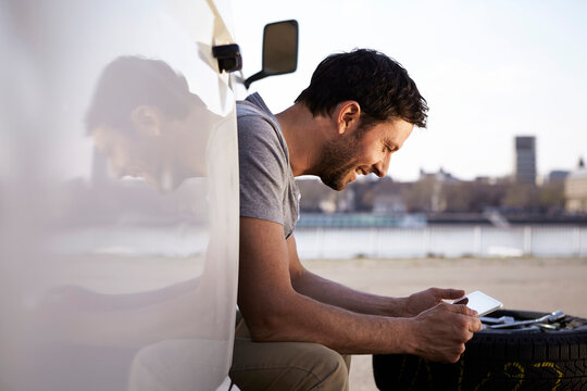 Man sitting in car looking at digital tablet