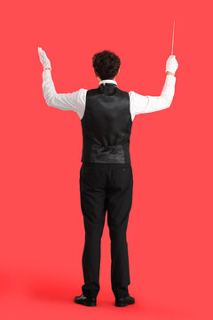 Young male conductor on red background, back view