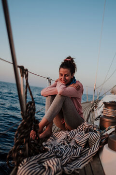 Smiling woman relaxing on a sailing boat at sunset