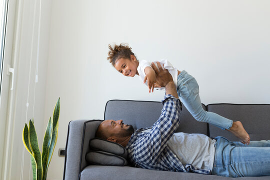 Happy father and daughter playing on couch at home