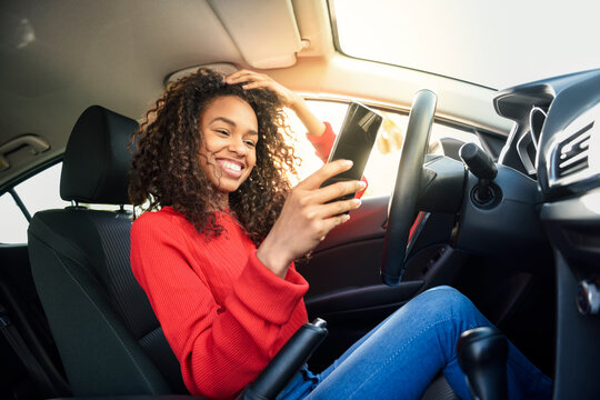 Happy young woman using cell phone in a car