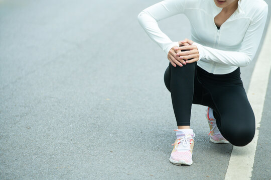 Cropped shot Woman Runner Suffering Knee Pain Injury During Outdoor Workout in Park