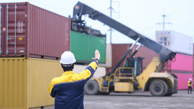 Industrial logistics worker directing container lifting operation at cargo shipping terminal