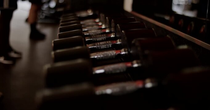 Close up of a rack featuring rows of black handheld weights in a fitness studio