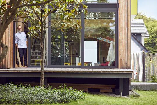 Thoughtful mature man standing at entrance of tiny house