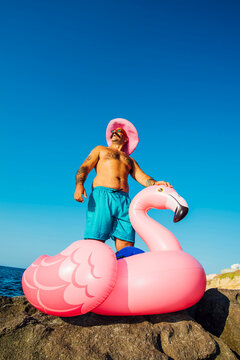 Man wearing hat standing on flamingo ring against clear sky