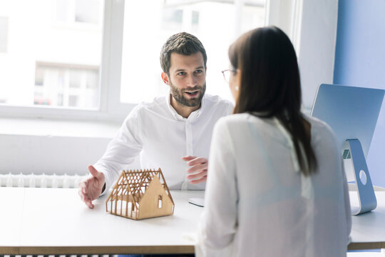 Man explaining architectural model to woman