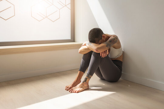 Sad woman sitting on floor by window
