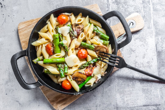 Pan of vegetarian pasta with asparagus, mushrooms, tomatoes and Parmesan cheese