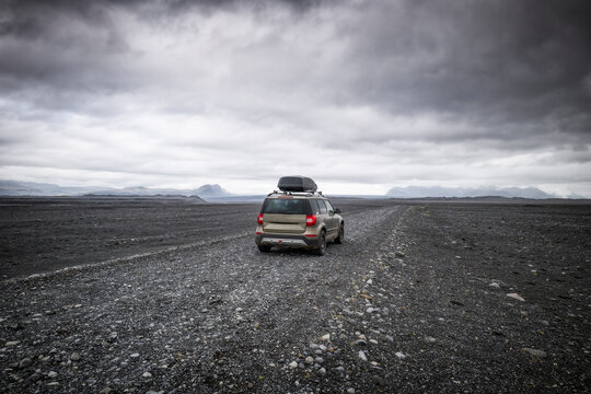 Lone 4x4 vehicle driving on gravel plain in Iceland