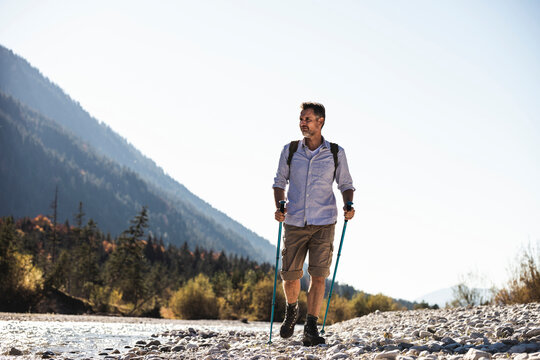 Austria, Alps, man on a hiking trip walking on pebbles along a brook