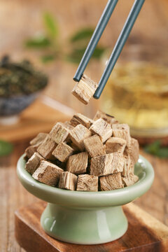Herbal Medicine Preparation - Pueraria Mirifica Root Cubes in Traditional Bowl with Tweezers