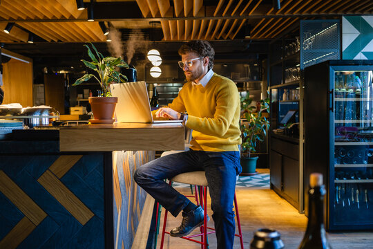 Businessman using laptop while sitting on seat at counter in cafe