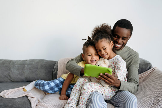 Smiling man with son and daughter using digital tablet on sofa