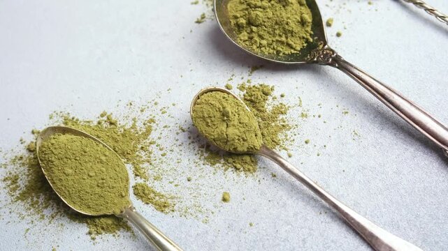 Green tea matcha powder on antique spoons scattered on a surface
