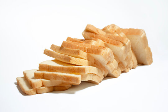 Multiple slices of white bread aligned in a diagonal stack, creating a simple bakery food composition on a clean white background.