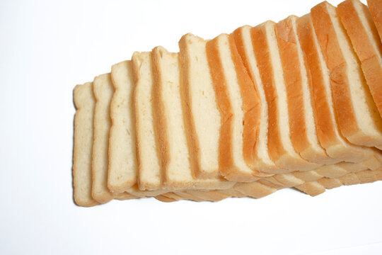 Top view of multiple slices of white bread arranged in a diagonal overlapping stack on a clean white background.