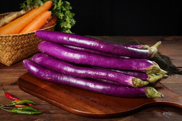 Fresh Purple Long Thread Eggplant from Yunnan Alpine Farms on Rustic Wooden Board with Organic Vegetables © LanThi