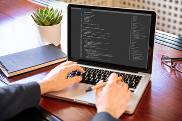 Fototapeta premium Man programming on a computer, office background
