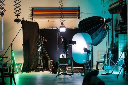 An inviting studio environment showcases multiple cameras, lighting equipment, and chairs, designed for conducting interviews or podcasts