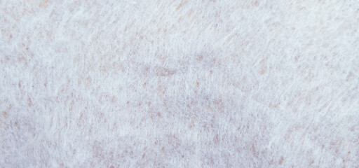 A soft, fibrous white non-woven cotton or felt texture backdrop with faint mottled brown speckles scattered across the textured surface © wiki