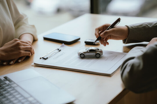 Businesswoman handing over a car key while signing a vehicle purchase or rental agreement, symbolizing automotive sales, leasing, and customer service.