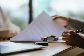 Fototapeta premium Businesswoman handing over a car key while signing a vehicle purchase or rental agreement, symbolizing automotive sales, leasing, and customer service.