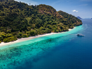 Obraz premium Aerial drone view of tropical landscape over Madam Beach of Nyaung Oo Phee Island with tour boat anchoring on the floating dock in the Mergui Archipelago, Myanmar. Beautiful Andaman sea in Burma