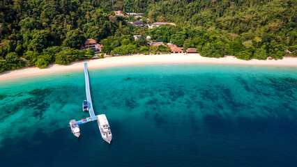 Aerial view of tropical beach landscape with floating jetty and tour boats anchoring in front at Nyaung Oo Phee island in Myanmar. Exotic resort for summer vacation in Andaman sea, Burma. © zephyr_p