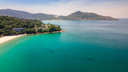 Fototapeta premium Aerial top view of Surin beach in Phuket, Thailand. Turquoise waves reach the Andaman sea coastline while tourists relaxing on the beach. Travel attraction for summer vacation