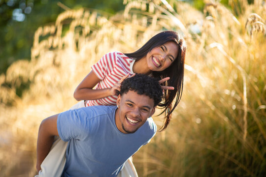 Playful young couple having fun together in golden summer field