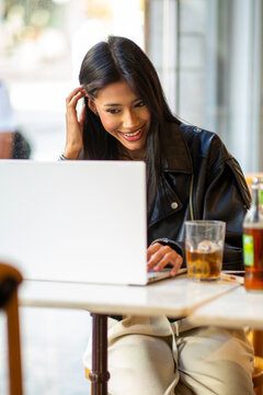Happy woman working remotely on laptop in cafe