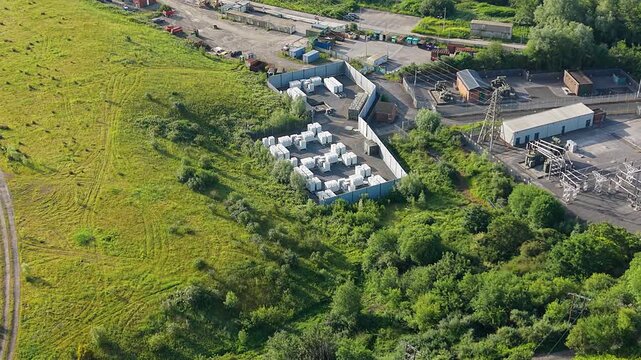 Wide Aerial Overview of Small Modular BESS Battery Energy Storage System with Lithium-ion Containers. Grid management, AI energy optimization, and sustainable infrastructure. UK. 4K.