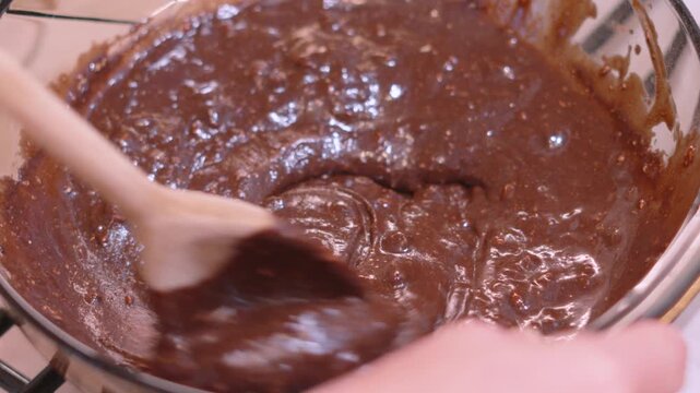 Stirring Luxurious Thick Chocolate Brownie Mix in Glass Dish. Glossy fudge batter, perfect for cooking tutorials and recipe video concepts. 4K.
