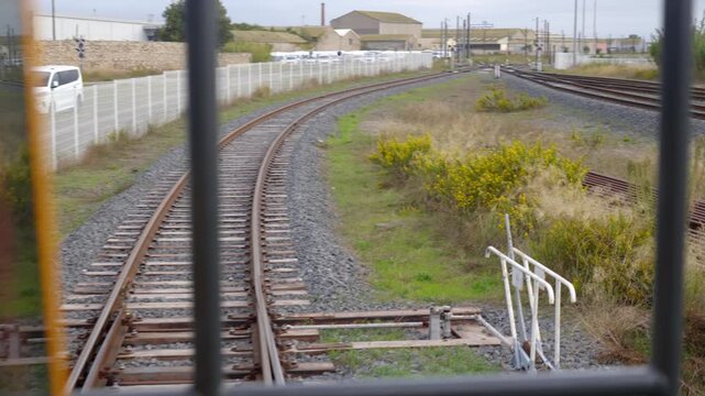 Inside a train cabin looking out over railway tracks and switches at a busy freight logistics terminal, showcasing industrial rail infrastructure.