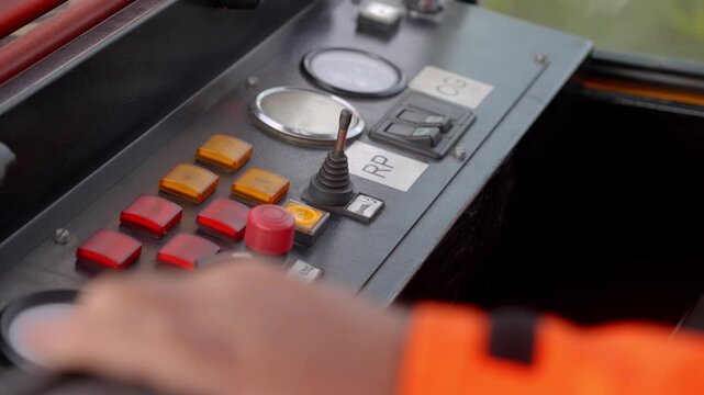 Operator hand using control panel with gauges and switches inside train cab