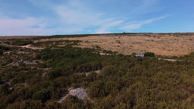 Modern camper van driving along country road on Pag Island, Croatia. Aerial side view following