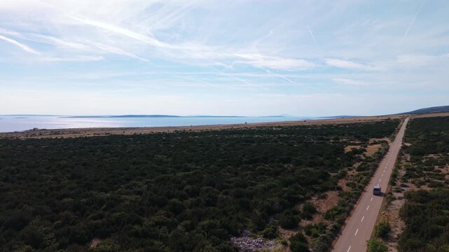 Aerial view tracking a camper van on its scenic drive along the Adriatic mediterranean coast. Car follow