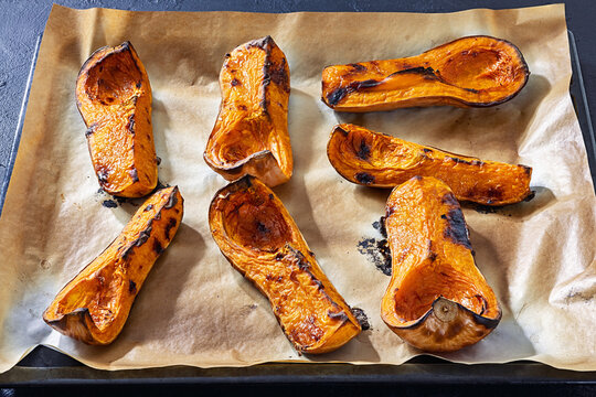 Baked butternut squash halves on a paper