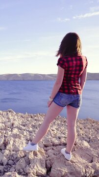 Woman sightseeing at sea from top of stones