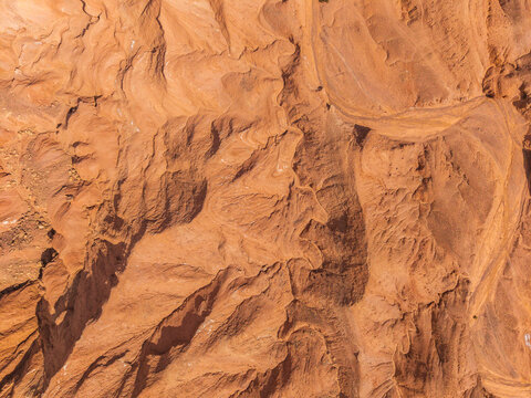 Aerial view of the rugged desert terrain at Devil's Throat Viewpoint, featuring deep eroded canyons, textured sandstone formations, and winding trails in Catarpe, Antofagasta, Chile.