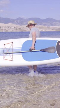 Person carry sup board in to water