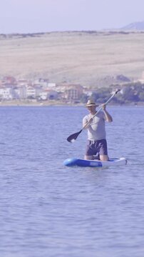 Male person on sup rowing in middle of sea