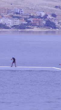 Person pulled by rope on wakeboard over stunts