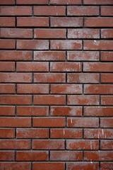 Fototapeta premium Vertical texture of a rustic red brick wall featuring weathered details and white paint splatters for industrial background