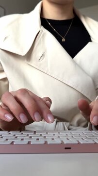 Close-up of a person typing on a stylish pink computer keyboard.