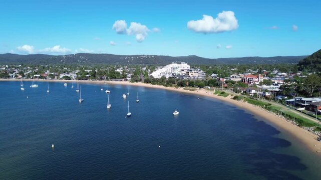 drone view Ettalong beach NSW Australia.View of the bay with boats and a town by the water on a sunny day near a large hill in New South Wales
