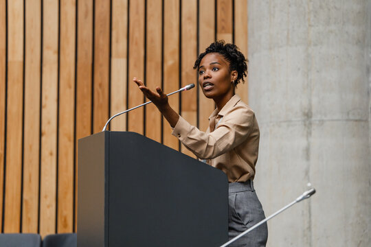 Woman giving a speech at a podium during a professional conference presentation