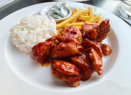 Delicious plate of chicken with rice, fries, and salad served at a restaurant during lunchtime