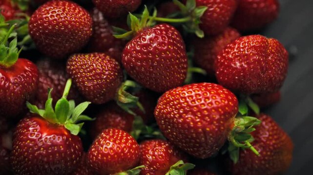 A top-down close-up of ripe red strawberries with green leaves in soft light. The volumetric image reveals the natural texture and graininess of the berries. An eco-friendly concept
